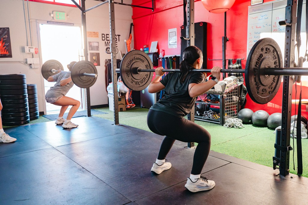 Athletes performing barbell squats during a small group training session